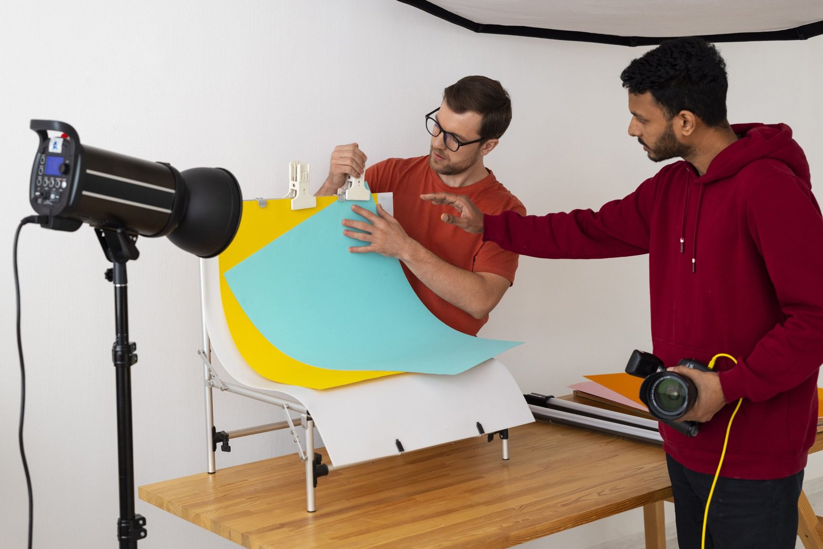 Equipo creativo ajustando fondo de colores durante sesión de fotografía en estudio.